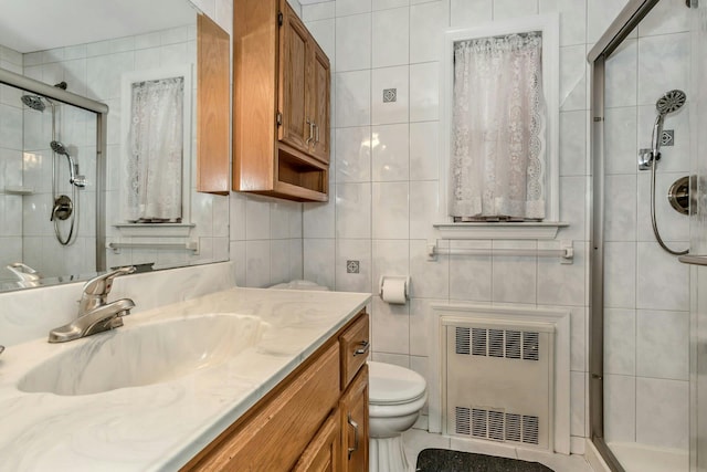 bathroom featuring vanity, radiator, toilet, tile walls, and an enclosed shower