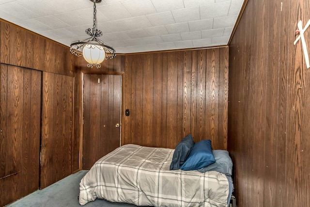 bedroom with wooden walls, a closet, and carpet