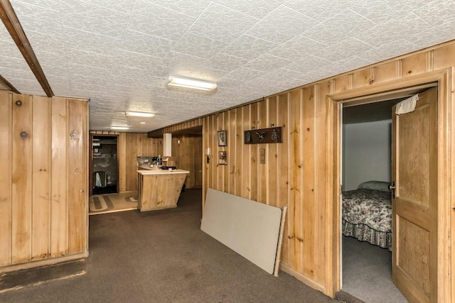 hallway with wood walls and dark colored carpet