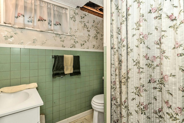 bathroom featuring vanity, tile walls, and toilet