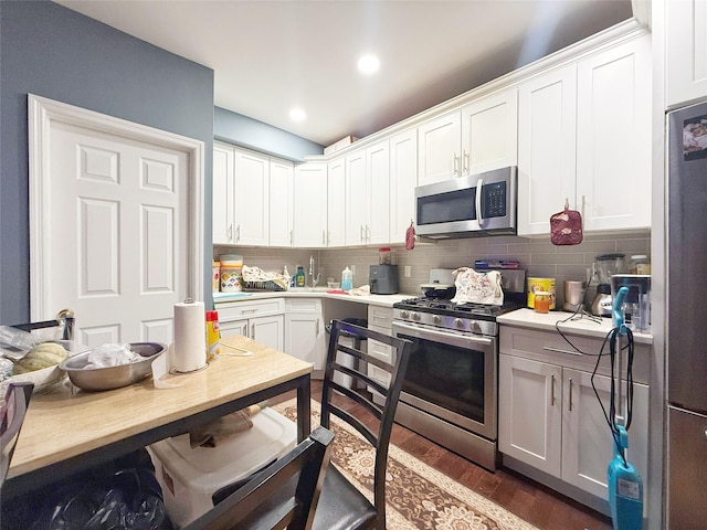 kitchen with decorative backsplash, white cabinetry, stainless steel appliances, and dark wood-type flooring