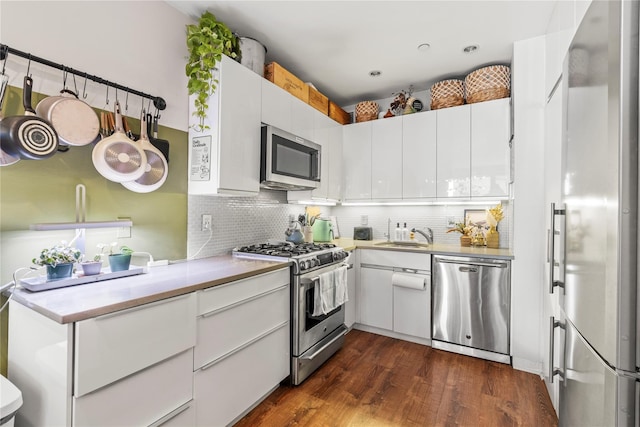 kitchen with decorative backsplash, appliances with stainless steel finishes, dark hardwood / wood-style flooring, and white cabinetry