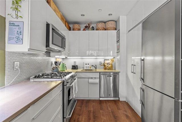 kitchen with dark hardwood / wood-style flooring, tasteful backsplash, premium appliances, sink, and white cabinets