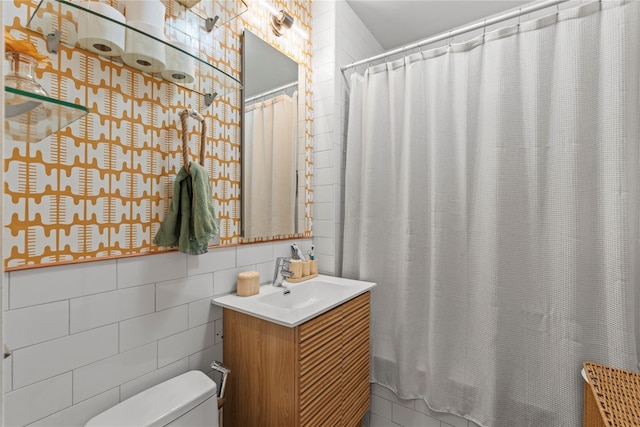 bathroom with walk in shower, vanity, toilet, and tile walls