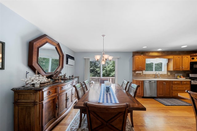 dining area with light wood-type flooring, sink, a wealth of natural light, and a chandelier