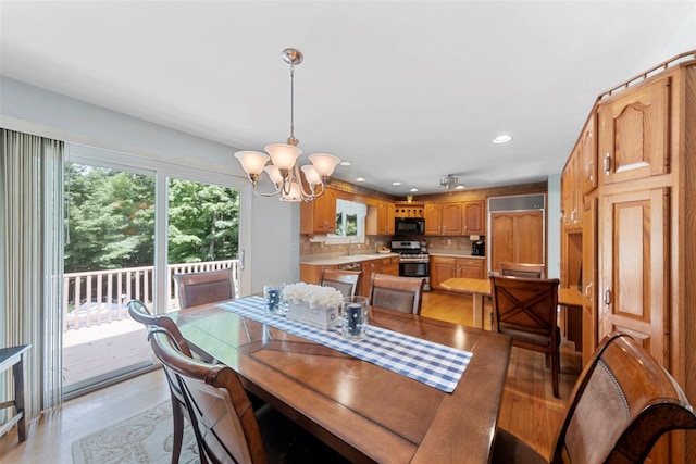 dining area with a notable chandelier, light hardwood / wood-style floors, and sink