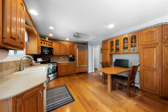 kitchen featuring ceiling fan, sink, light hardwood / wood-style floors, decorative backsplash, and stainless steel range with gas stovetop