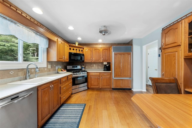 kitchen with ceiling fan, sink, light hardwood / wood-style flooring, decorative backsplash, and appliances with stainless steel finishes