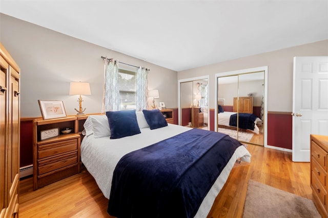 bedroom featuring multiple closets, light hardwood / wood-style floors, and a baseboard radiator