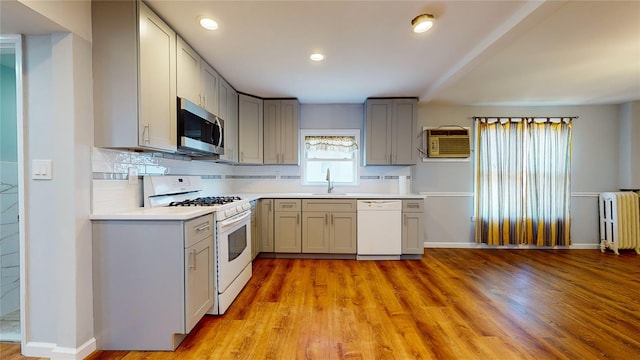 kitchen featuring radiator, gray cabinetry, white appliances, sink, and light hardwood / wood-style floors