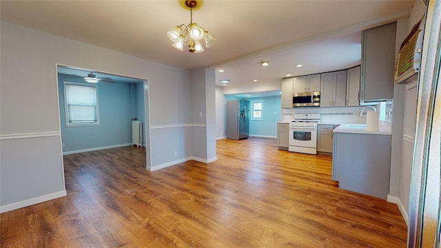 kitchen featuring appliances with stainless steel finishes, gray cabinets, light hardwood / wood-style flooring, and pendant lighting