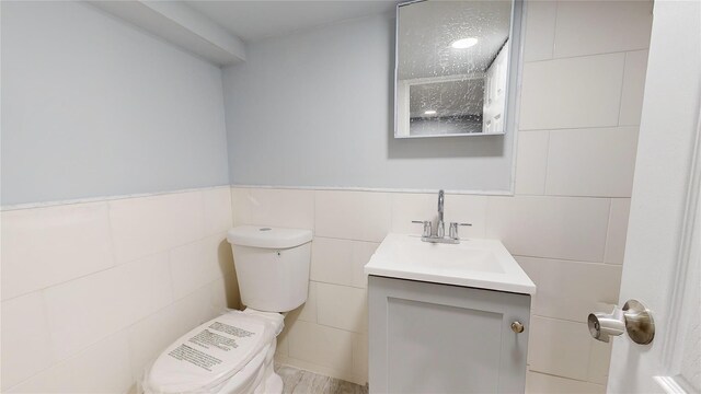 bathroom featuring vanity, toilet, and tile walls