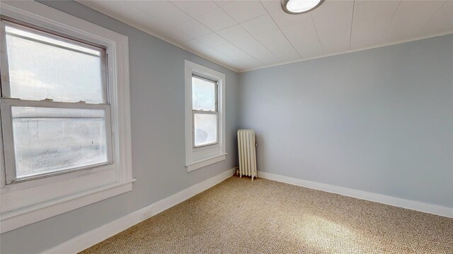 spare room featuring carpet, crown molding, and radiator