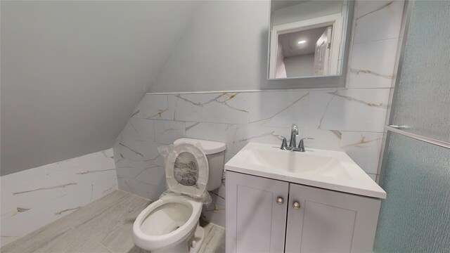 bathroom with vanity, tile walls, and toilet