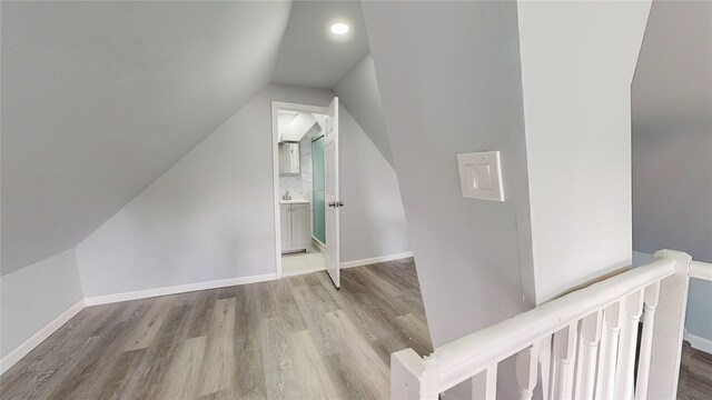 bonus room featuring sink, light hardwood / wood-style floors, and vaulted ceiling