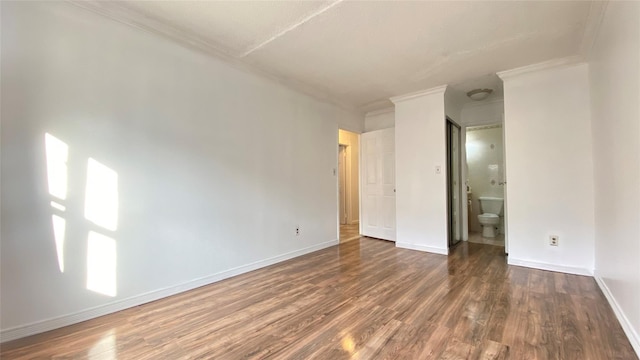 unfurnished bedroom with connected bathroom, crown molding, and dark wood-type flooring