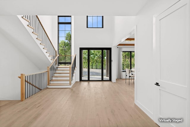 foyer with a towering ceiling and light hardwood / wood-style flooring