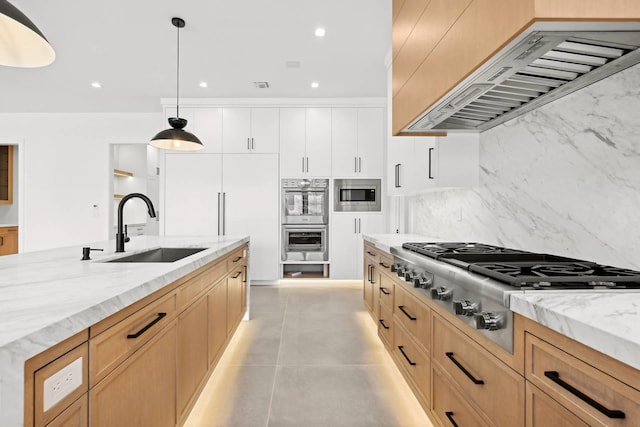 kitchen with sink, white cabinets, hanging light fixtures, built in appliances, and custom range hood