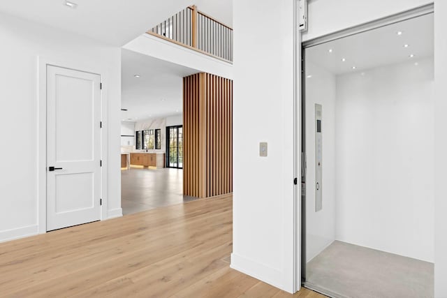 hallway featuring elevator and light wood-type flooring