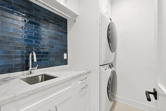 laundry room with cabinets, stacked washing maching and dryer, and sink