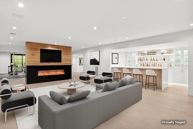 living room featuring bar area, a fireplace, and light hardwood / wood-style floors