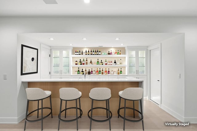 bar featuring white cabinets and light wood-type flooring