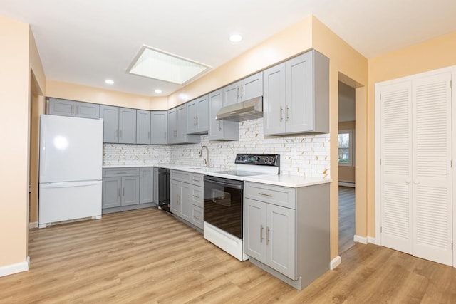 kitchen featuring gray cabinets, light hardwood / wood-style floors, and white appliances