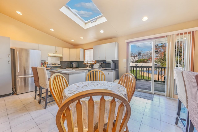 dining space with light tile patterned floors and lofted ceiling with skylight