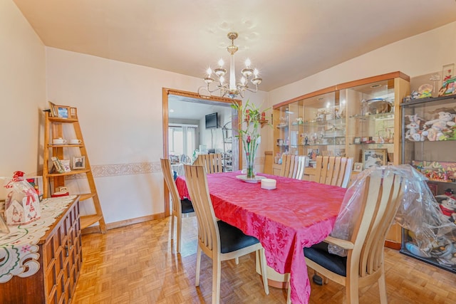 dining space with light parquet floors and an inviting chandelier