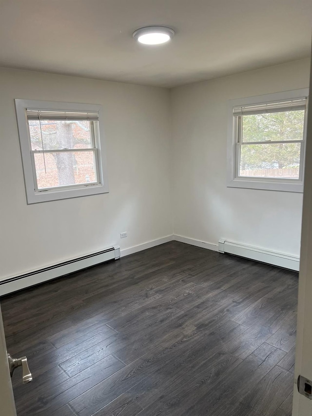 unfurnished room with a healthy amount of sunlight, dark wood-type flooring, and a baseboard heating unit