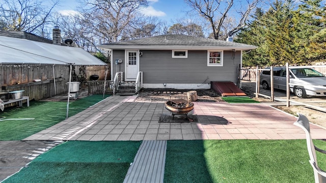 back of property with a fire pit and a patio area