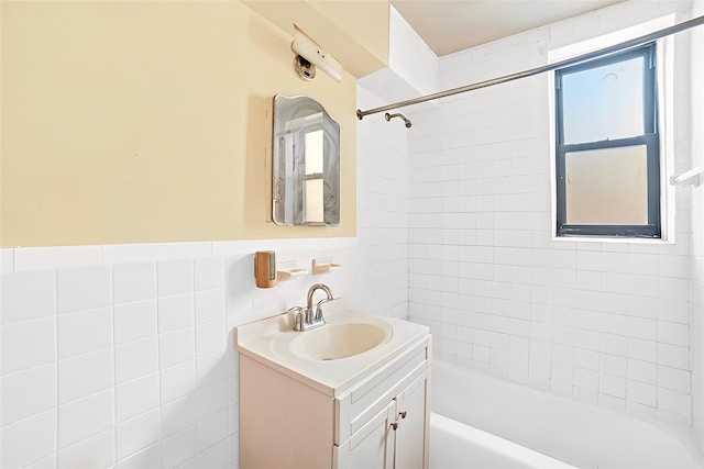 bathroom with tile walls, tiled shower / bath, and vanity