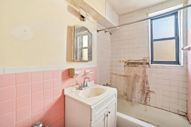 bathroom featuring tiled shower / bath combo, tile walls, and vanity