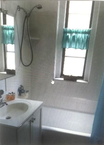 bathroom featuring plenty of natural light, shower / bath combination with curtain, and vanity