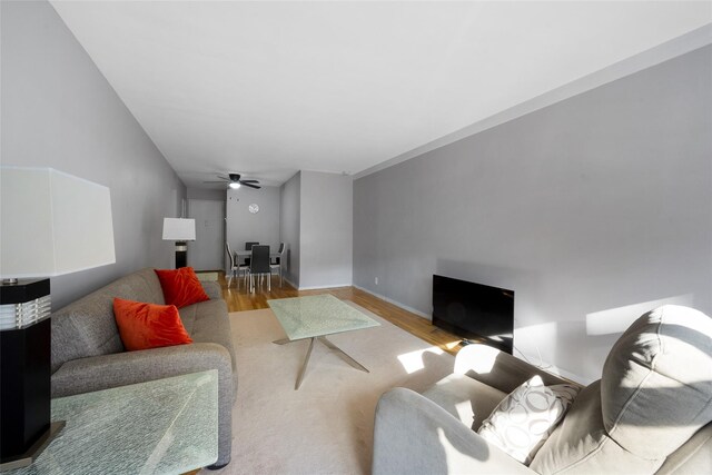 living room with ceiling fan, light wood-style flooring, and baseboards