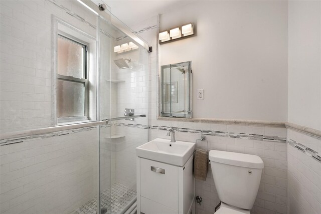 bathroom featuring toilet, a shower stall, vanity, and tile walls