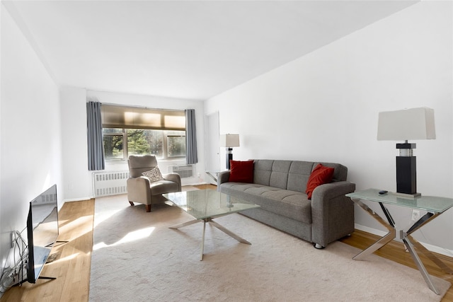 living room with light wood-type flooring, baseboards, a fireplace, and radiator heating unit