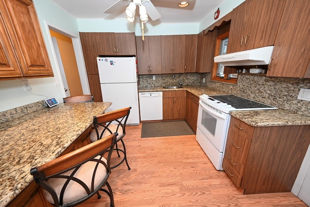 kitchen featuring sink, light hardwood / wood-style flooring, range hood, stone countertops, and white appliances