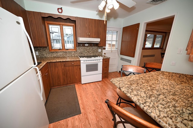 kitchen featuring white appliances, radiator, decorative backsplash, ceiling fan, and light wood-type flooring