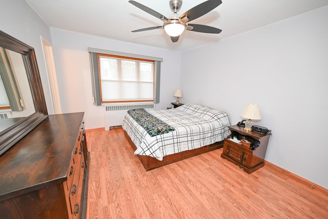 bedroom featuring radiator heating unit, light hardwood / wood-style floors, and ceiling fan