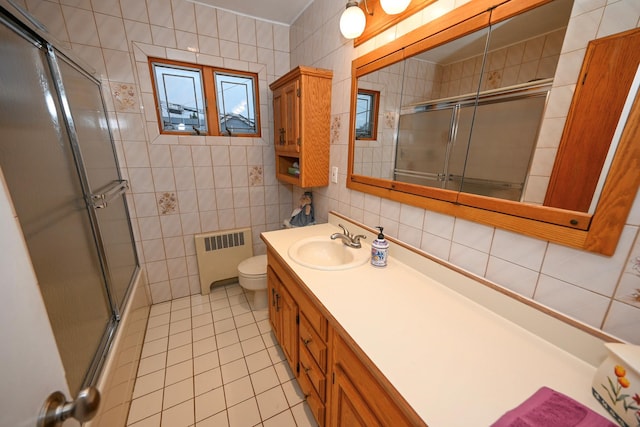 bathroom with radiator heating unit, vanity, tile patterned floors, and tile walls