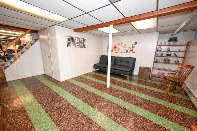 basement featuring a drop ceiling and wooden walls