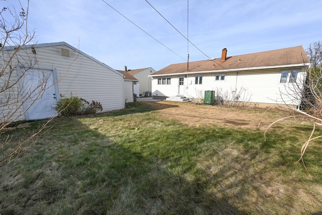 rear view of property featuring central air condition unit and a lawn