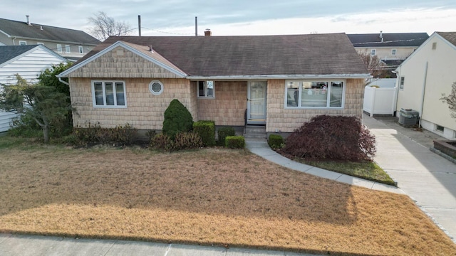 single story home with central AC unit and a front yard