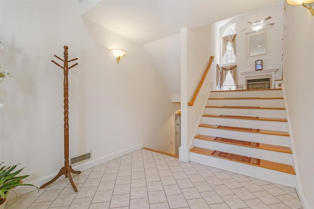 stairs with tile patterned floors, ceiling fan, and lofted ceiling