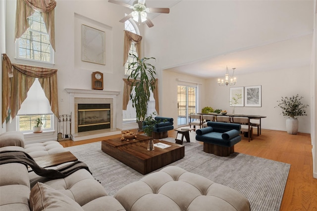 living room featuring ceiling fan with notable chandelier, light hardwood / wood-style floors, and a towering ceiling