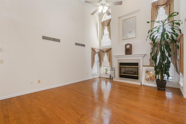 unfurnished living room with a healthy amount of sunlight, a high ceiling, and light hardwood / wood-style flooring