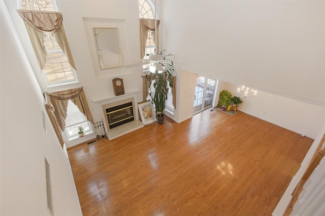 unfurnished living room with a chandelier, plenty of natural light, a towering ceiling, and hardwood / wood-style floors