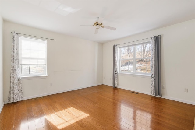 unfurnished room with ceiling fan, plenty of natural light, and wood-type flooring