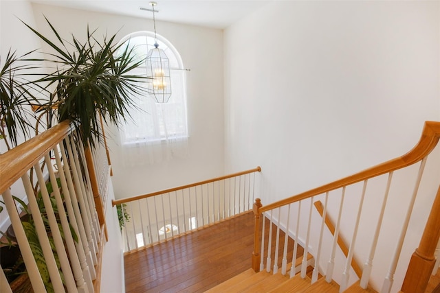 stairs with hardwood / wood-style flooring and a chandelier